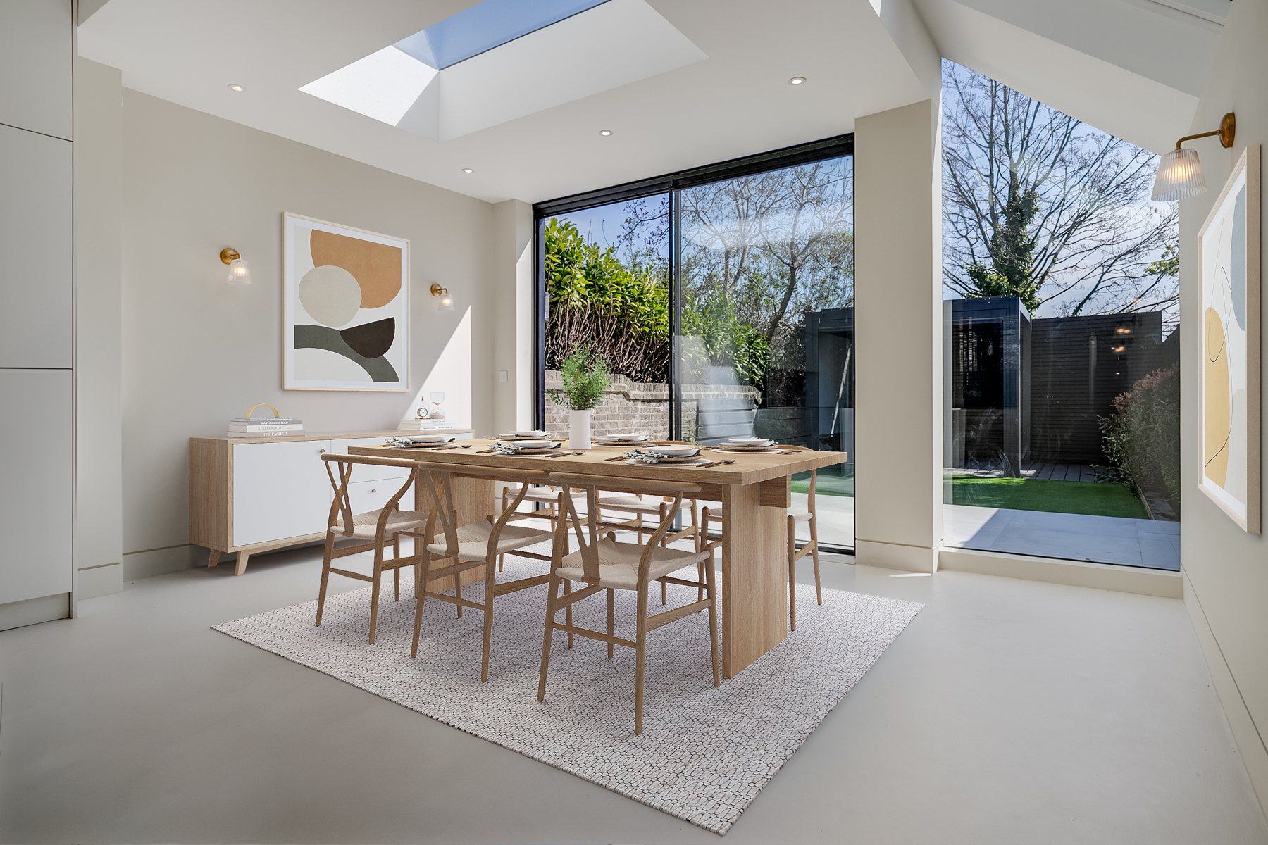Dining area under a rooflight beside large slim sliding doors