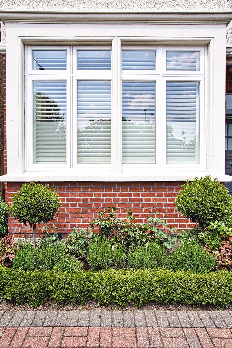 Bay window with white timber casements above a front garden
